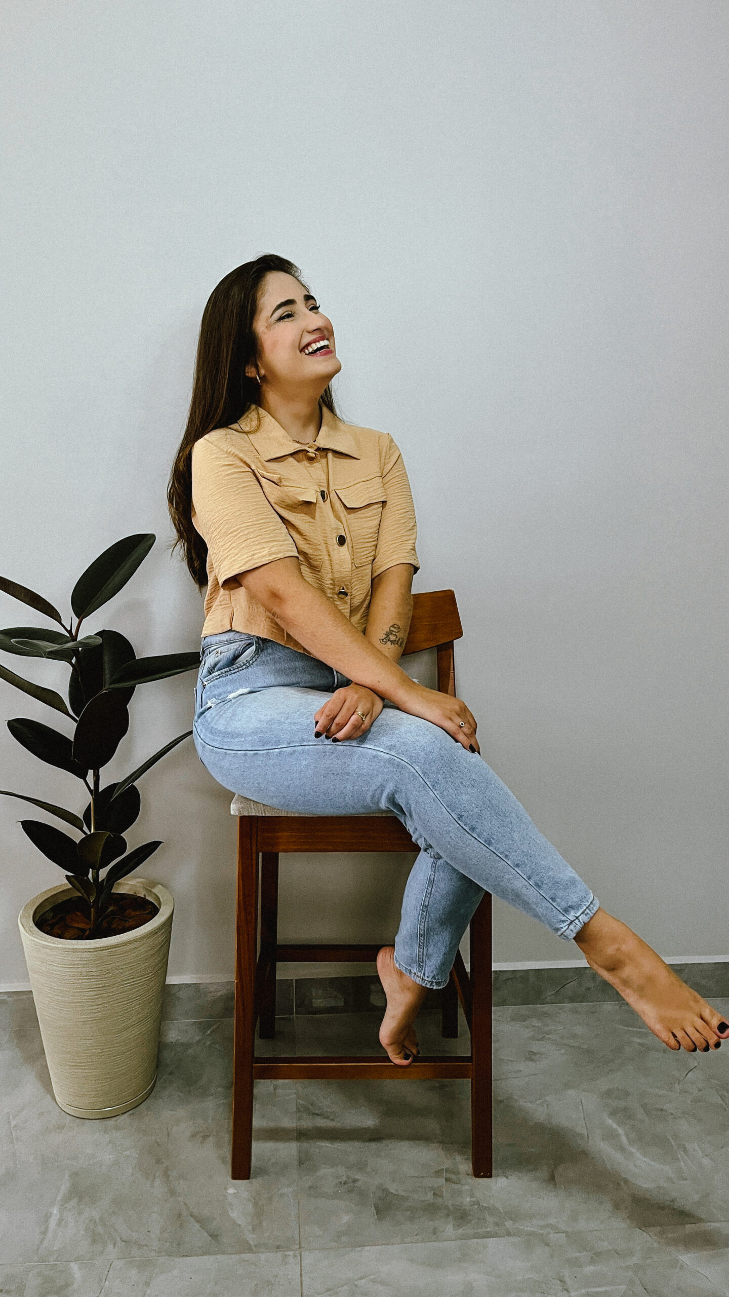 Foto de Luana morais sentada de pernas cruzadas em uma banqueta sorrindo